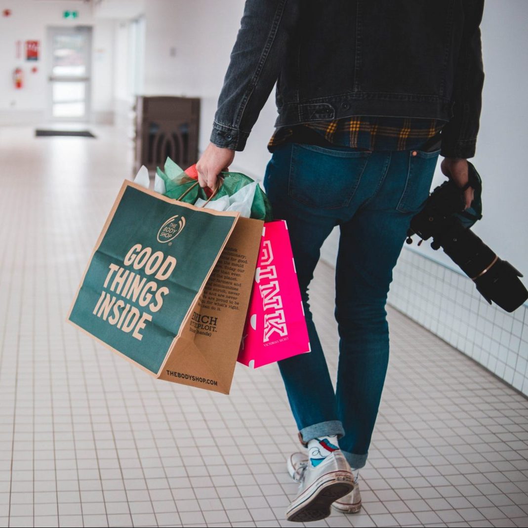person walking while carrying a camera and paper bags